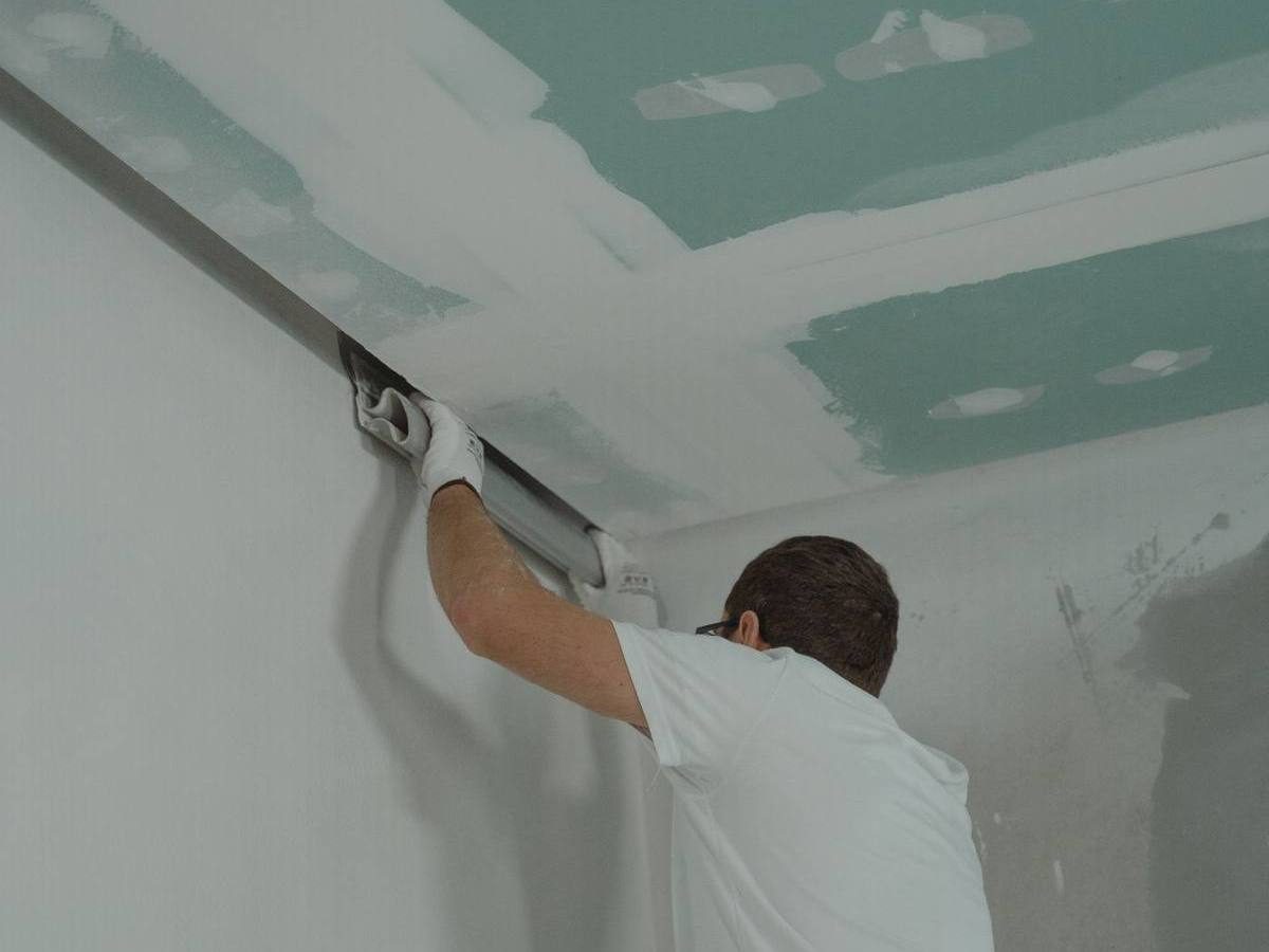 Worker replacing drywall after water damage repairs