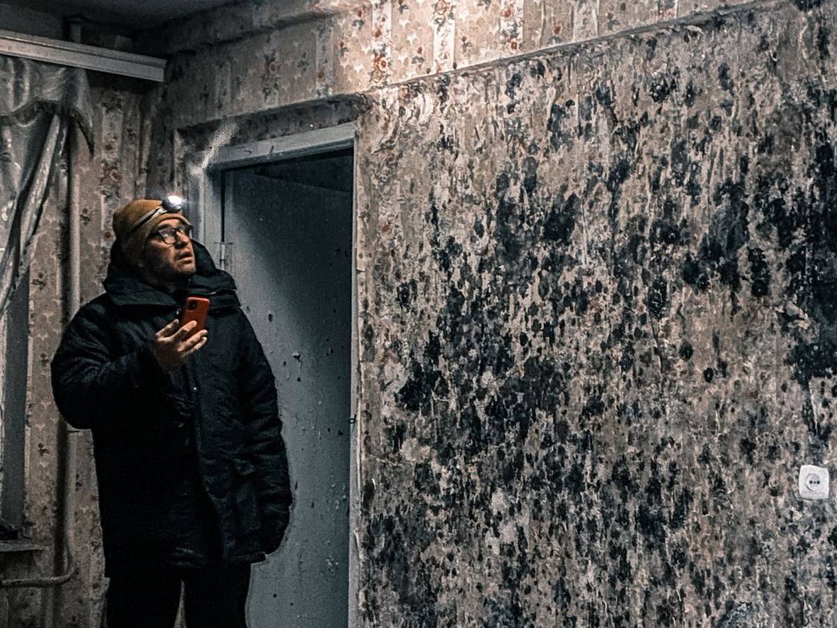 Man inspecting mold growth on walls after water damage