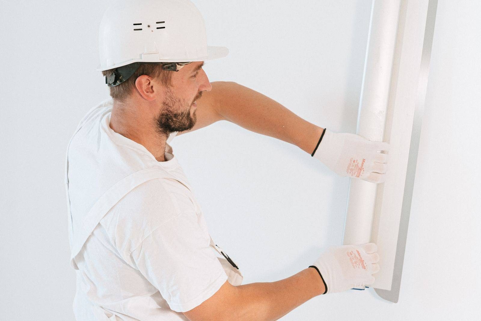 Restoration worker in a hard hat installing a new wall panel